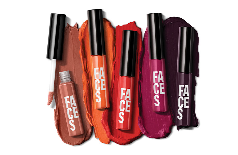 Labiales Líquido Mate Faces destapados con brochazos de labial aplicados sobre un fondo unicolor.